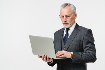 Smart caucasian elderly senior businessman ceo boss teacher professor working on laptop online, reading news, watching webinars, e-commerce isolated in white background