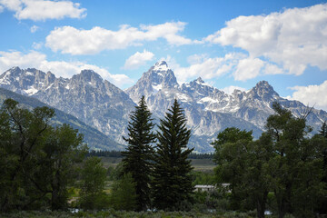 Snow capped mountains with fluffy clouds in blue sky