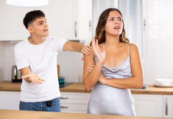Young husband is dissatisfied with the act of his wife, scolding her for it in the kitchen and pointing out her mistakes