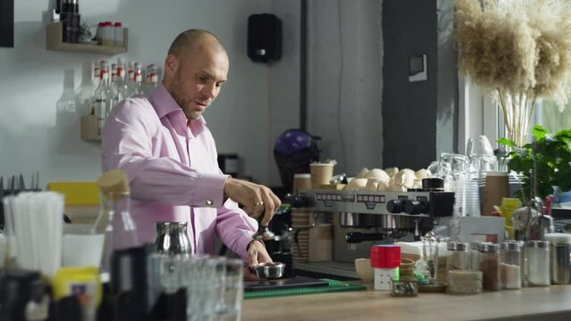 The profession of a barista in a cafe. The man presses the coffee in a templer and starts to prepare it. The process of making a latte. High quality 4k footage