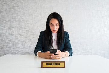 Young caucasian brunette business woman director in office hold smartphone read news surprised in shock at work