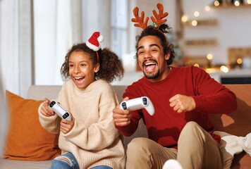 African american family father and daughter laugh and play video games together using a video game...