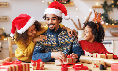 Happy ethnic family father and children pack Christmas gifts