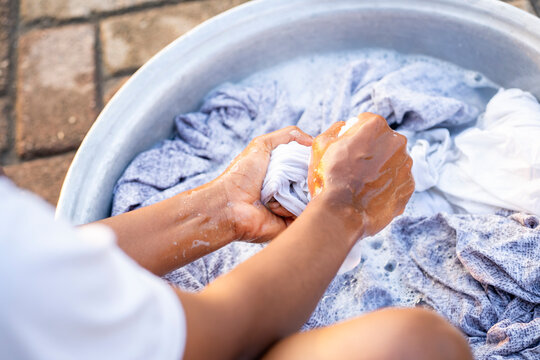 close up image of african squeezing a wet material, basin in front- hand wash concept