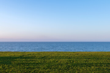 Fototapeta na wymiar Coast of the Baltic Sea in the autumn evening. Lawn, sea and evening sky