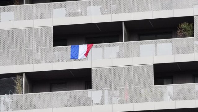 Telephoto view over French flag seen hanging from the balconies of modern apartment building in the center of Strasbourg prior to the WOrld Cup 