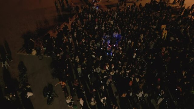 Aerial drone shot above crowd at open-air concert at night on the coast