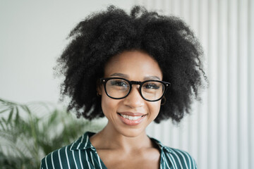 Portrait of a smiling freelancer woman in the office. The designer looks at the camera with glasses.