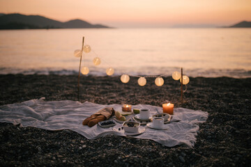 Romantic picnic by the sea at sunset.