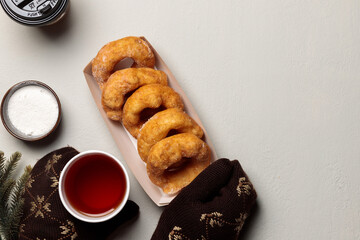 Hands in knitted mittens hold a drink in a disposable cup and a paper plate with donuts. Copy of the space