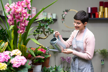 Young woman professional florist working with flowers in her flower shop in summer	