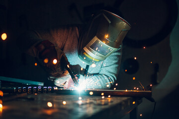 Man worker welding metal with welding machine in a factory or workshop