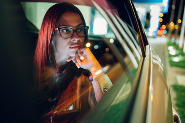 Business woman sitting in a backseat of a car or taxi at night