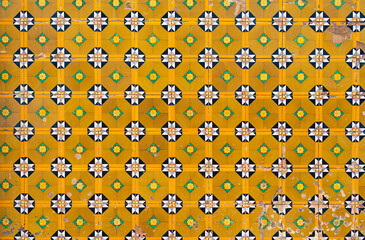 Fragment of building wall with yellow floral ceramic wall tiles Azulejo Abstract decorative background textured ornate pattern. Traditional ornate Portuguese architecture 