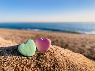 Fototapeta na wymiar Low anngle close-up view of two candy hearts on the beach on a cheerful sunny day