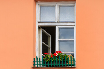 Fototapeta na wymiar Beautiful classic wooden window with flowers on the windowsill in minimalist European architecture. Cozy tourist town
