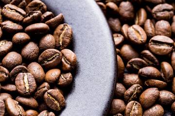 Roasted coffee beans on a plate, on a dark background, close-up image, space for text