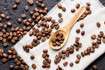 Roasted coffee beans with wooden spoon, closeup image, space for text