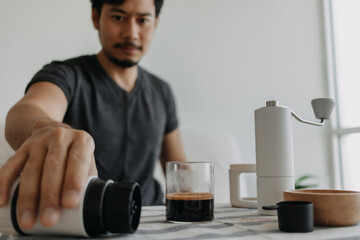Asian man make and drink his own french press coffee.
