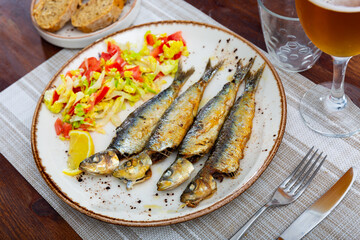 Appetizing fried sardines with a light vegetable salad made from lettuce, tomatoes and red pepper....