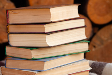 a close stack of old books on the woolen blanket  on wooden background in vintage style. Literature, education, hobby, reading and lifestyle. Knowledge and wisdom