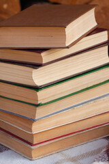 a close stack of old books on the woolen blanket  on wooden background in vintage style. Literature, education, hobby, reading and lifestyle