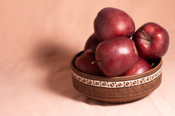 still life red apples in a clay plate with a pattern on a pink background