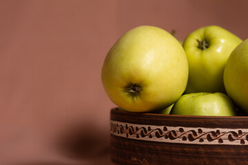 Close up still life golden apples in a clay plate with a pattern on a pink background
