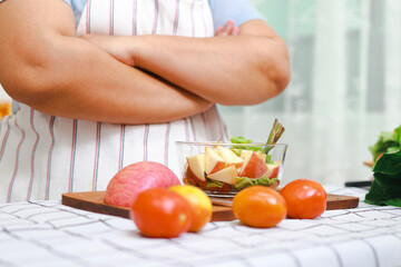 Fat Asian woman cooking in the kitchen Slice organic vegetables and fruits into glass cups. Make a healthy low-calorie salad. health care concept Eat healthy food to lose weight.