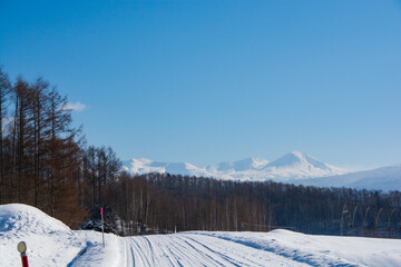 冬の晴れた日の雪道と山並み　大雪山
