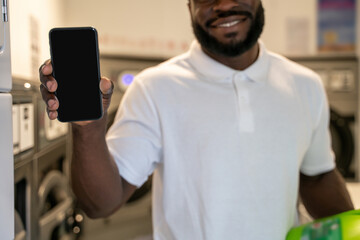 Joyous guy standing in a self-service laundry room