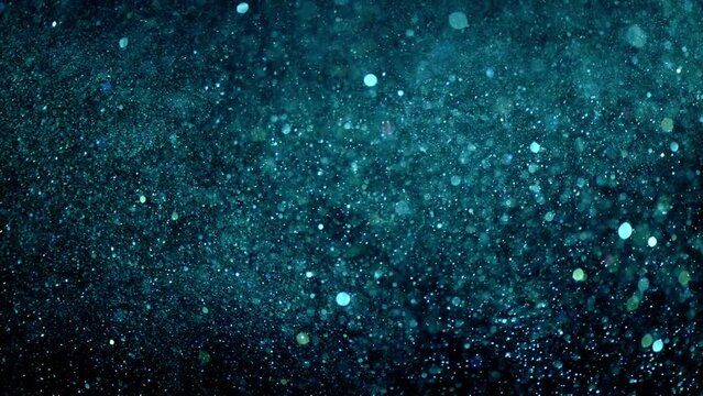 Glitter background in 4k resolution. with alpha channel. Real particles flying in wind on black background, shot with depth of field. 