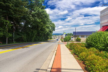 straight road through a small town stretching towards the horizon. The road along the hotels markets and gas stations. Blue sky and magnificent clouds.