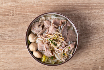 Rice noodles soup with pork in bowl on wooden background, Asian food, Table top view