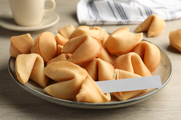 Tasty fortune cookies and paper with prediction on wooden table, closeup. Space for text