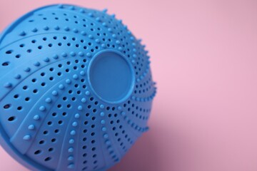 Laundry dryer ball on pink background, closeup. Space for text