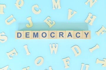 Democracy government form concept. Wooden blocks typography flat lay in blue background.