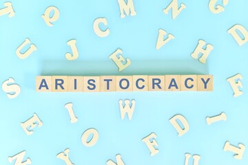 Aristocracy government form concept. Wooden blocks typography flat lay in blue background.
