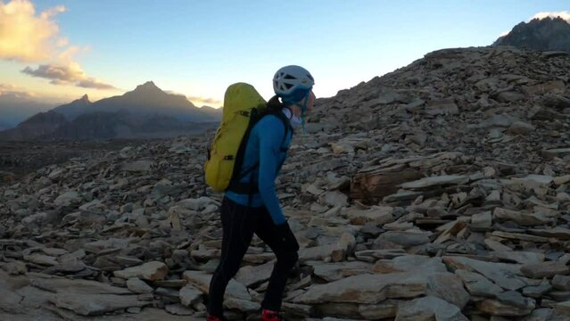 Young woman alpinist hiking on a mountain at the sunrise slow motion