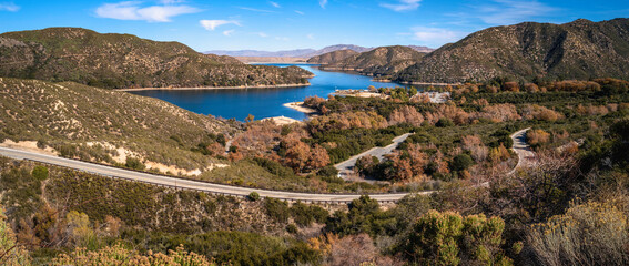 Tranquil autumn forest lake landscape with curving paved road at Silverwood Lake along Rim of the...