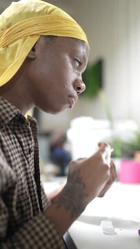 Black woman in a yellow durag putting in contact lenses