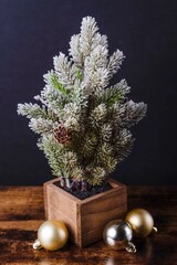 Frosted miniature evergreen tree with ornaments and pinecones