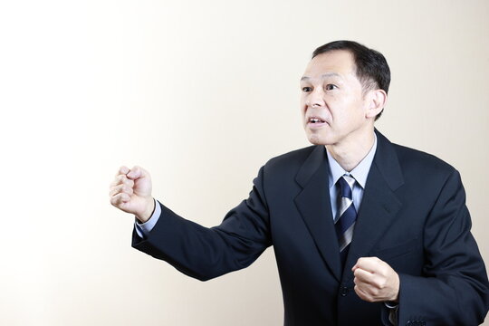 Middle-aged Japanese male businessman wearing navy blue suit on white background. Conceptual image of a project proposal, strategic business success and negotiation closing.