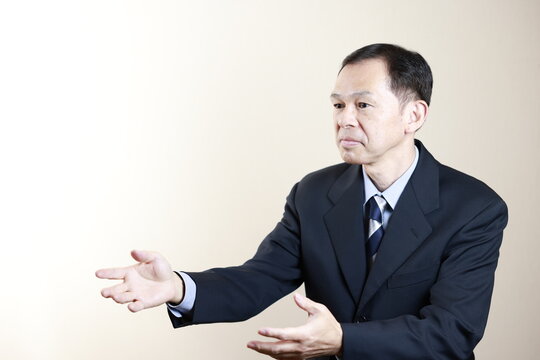 Middle-aged Japanese male businessman wearing navy blue suit on white background. Conceptual image of a project proposal, strategic business success and negotiation closing.