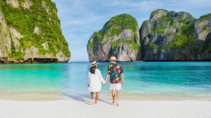 Thai women and caucasian men with a hat walk on the beach of Maya Bay beach Koh Phi Phi Thailand