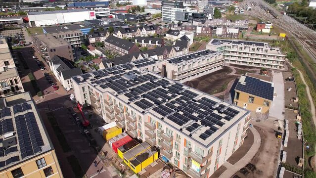 Rooftops full of solar panels aerial pan showing social housing market collective building Ubuntuplein project in Zutphen, The Netherlands. Dutch engineering real estate investment urban development