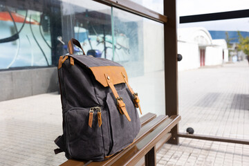 A hiking bag stands on benches at a bus stop with no close-ups of people.