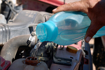 latin man hand pouring water on truck radiator