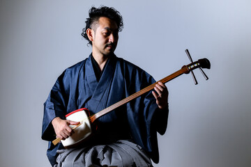 Middle-aged Japanese man playing the 「shamisen」
