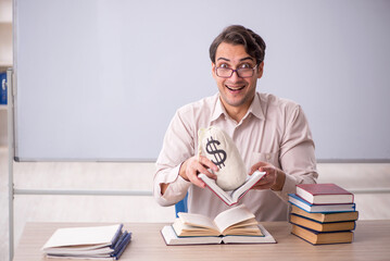 Young male student holding moneybag in the classroom